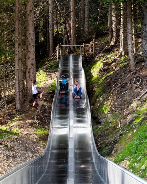 Family hotel in Bramberg: Smaragdhotel Tauernblick Two people sliding together down a metal slide in the forest