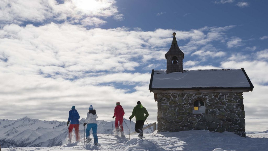 Hotel in Salzburgerland: Smaragdhotel Tauernblick Four winter hikers walking with poles beside a snow-covered chapel in the mountains