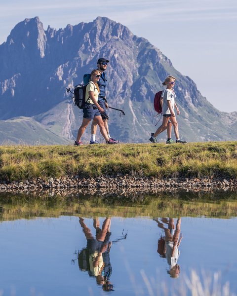 Family hotel in Bramberg: Smaragdhotel Tauernblick Family hiking by a lake with mountain backdrop on a clear day