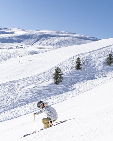 4 Sterne Hotel in Salzburgerland: Smaragdhotel Tauernblick Skifahrer auf schneebedecktem Hang mit Bäumen bei klarem Himmel