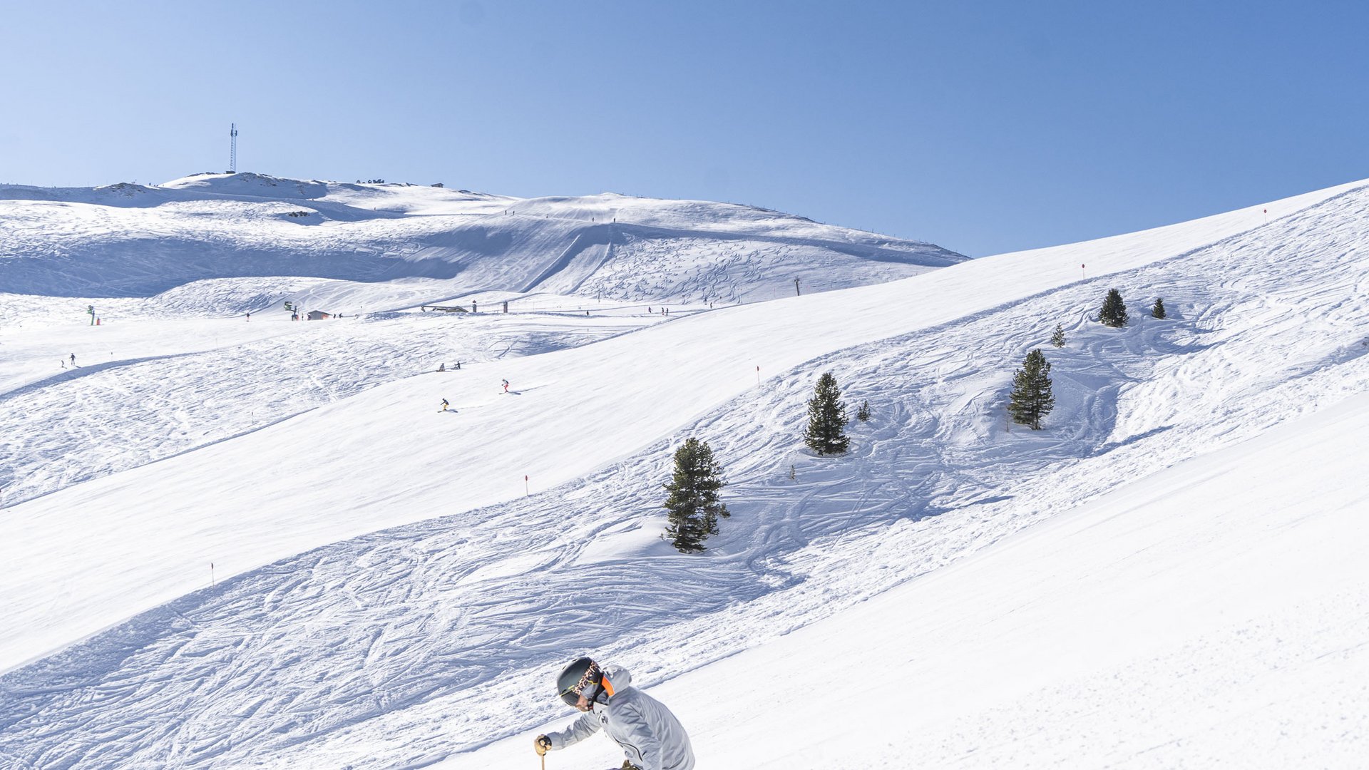 Skiing holidays in Salzburgerland: Smaragdhotel Tauernblick Skier descending snowy slope with trees under clear blue sky