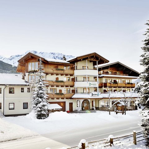 Salzburgerland: hotel jobs Hotel building in winter with snow-covered fir trees and mountains in background