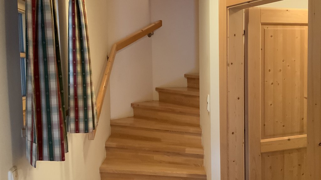 Das Ferienhaus Smaragd: ein wahres Juwel Holztreppe mit Handlauf in einem warm beleuchteten Flur neben Tür und Fenster mit Vorhängen