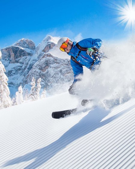 4 Sterne Hotel in Salzburgerland: Smaragdhotel Tauernblick Skifahrer fährt auf frisch präparierter Piste bei Sonnenschein im Gebirge