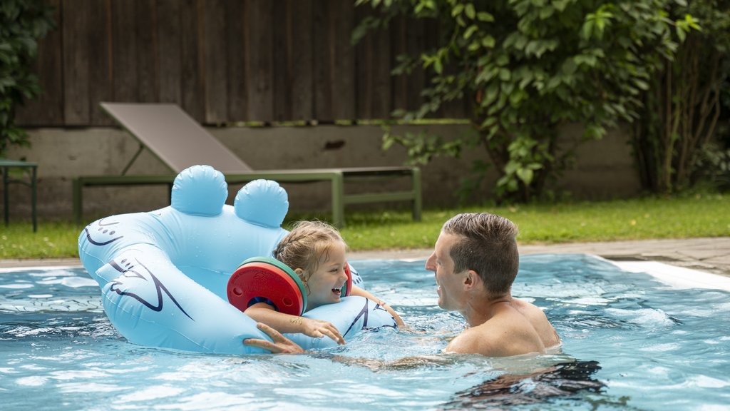Familienhotel im Salzburger Land: Smaragdhotel Tauernblick Vater spielt mit Kind in blauem Planschbecken im Garten