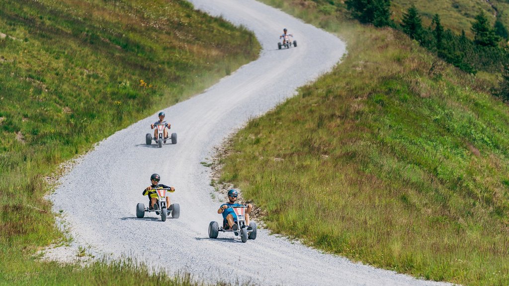 Familienhotel im Salzburger Land: Smaragdhotel Tauernblick Vier Fahrer auf dreirädrigen Karts fahren auf einem kurvigen Schotterweg durch eine grüne Landschaft