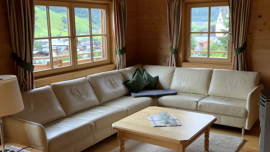 Das Ferienhaus Smaragd: ein wahres Juwel Wohnzimmer mit hellem Ledersofa, Holzwänden und Fenstern mit Blick auf grüne Hügel