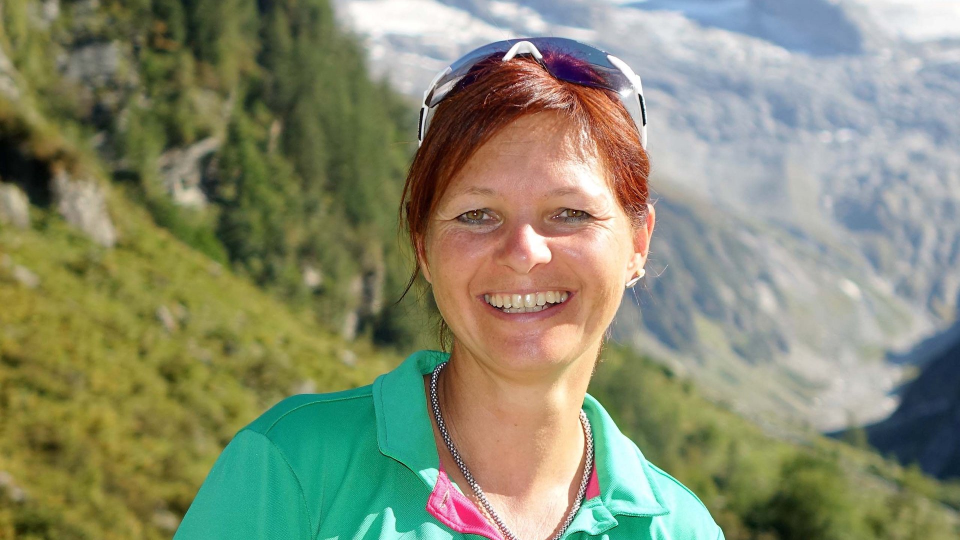 Wildkogel: a hotel with an eye for the extraordinary Smiling woman in green shirt with mountains, trees, and snow in the background