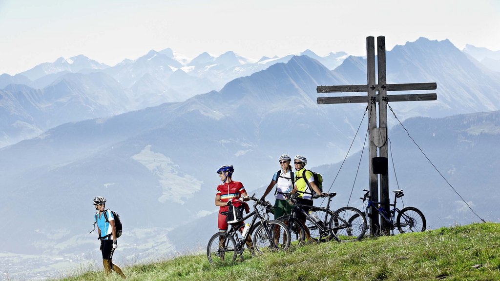 Hohe Tauern National Park: holiday for bikers Four cyclists on a mountain peak with a cross and alpine scenery