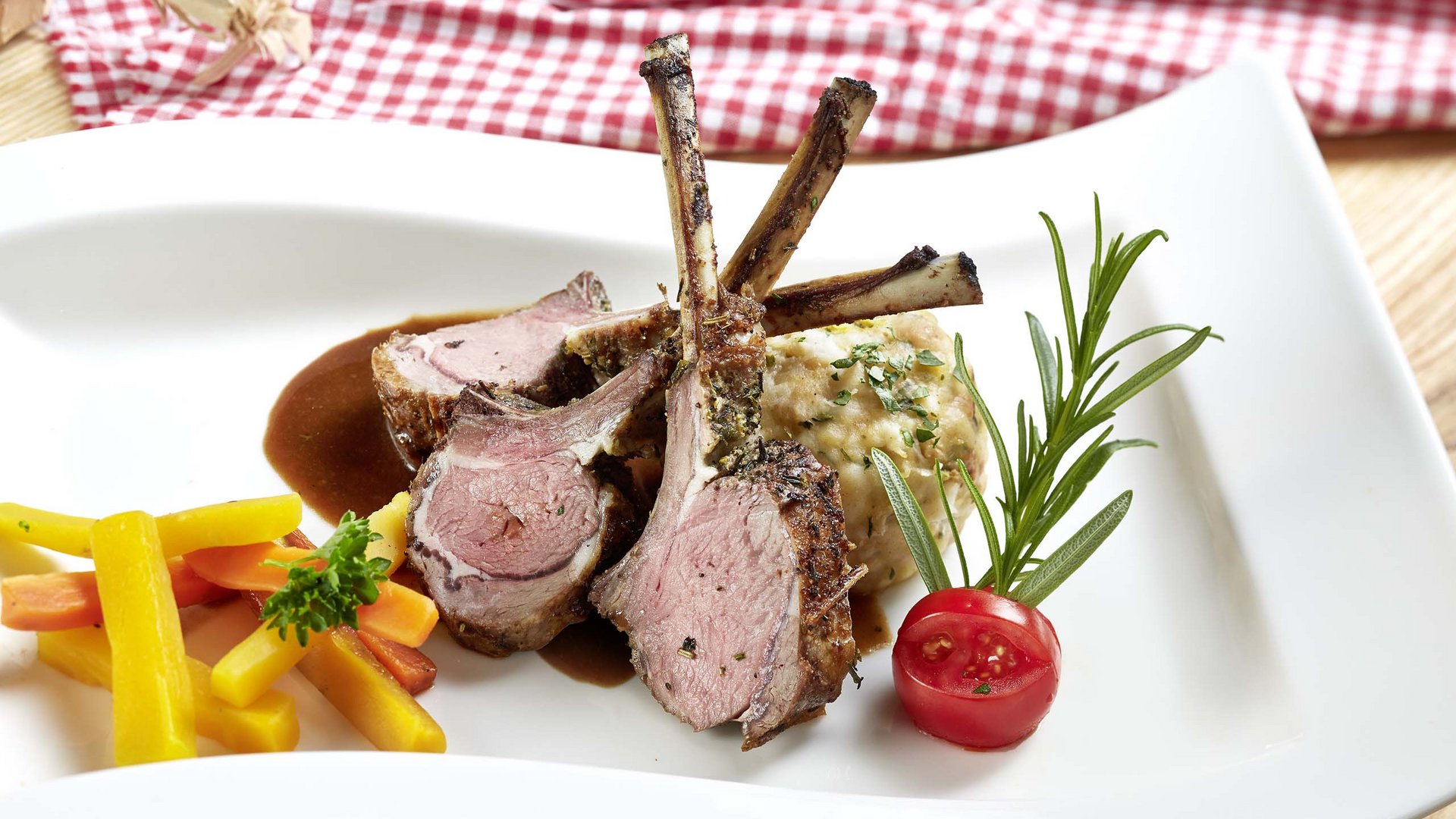 Salzburgerland: wellness hotel with 4 stars and cuisine Lamb chops with mixed vegetables, potato dumpling, and herbs on a white plate
