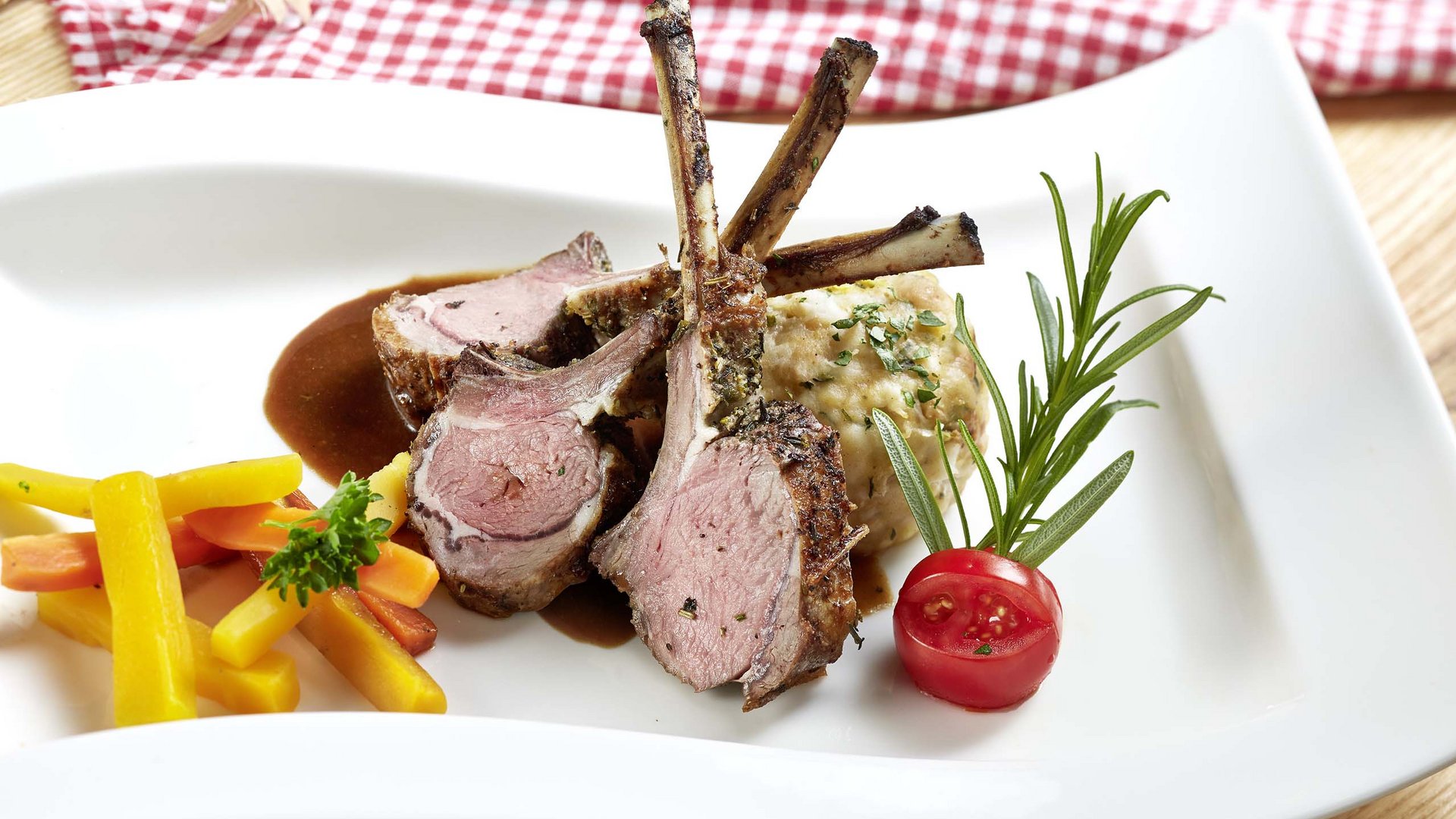 Salzburgerland: hotel jobs Lamb chops with mixed vegetables, potato dumpling, and herbs on a white plate