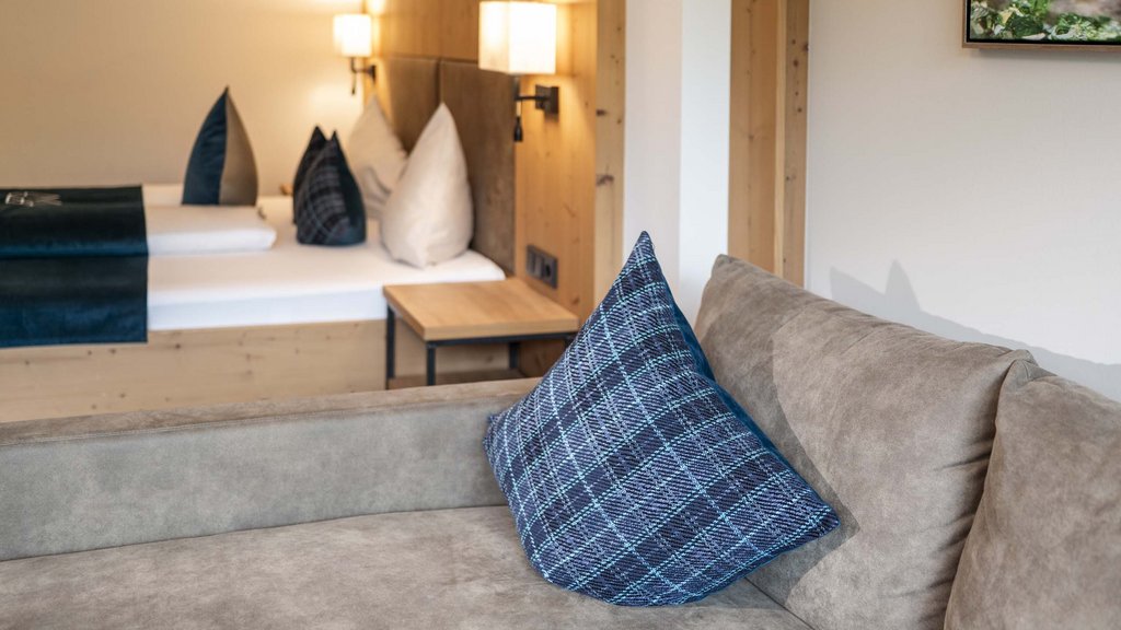 Bramberg am Wildkogel: accommodation Cozy living room with gray sofa, blue pillows, and wooden wall with lighting