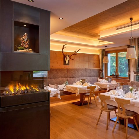 Accommodation near Wildkogel: Smaragdhotel Tauernblick Cozy restaurant area with fireplace, wooden furniture, and deer antlers on the wall