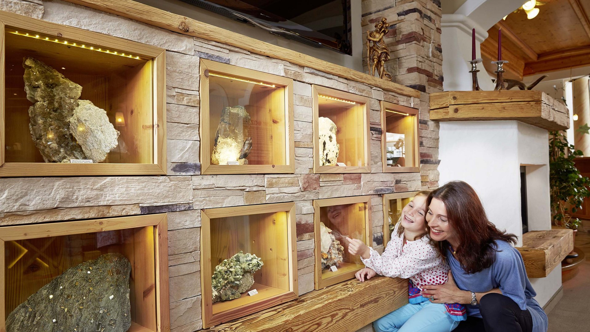 Our Smaragdhotel in Bramberg: green gold Mother and daughter looking at minerals in lit display cases on a stone wall