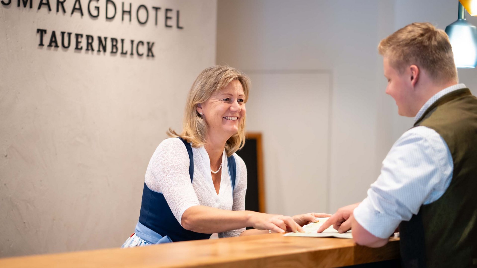 Smaragdhotel Tauernblick – your 4-star hotel near Wildkogel Receptionist welcomes guest at Smaragdhotel Tauernblick
