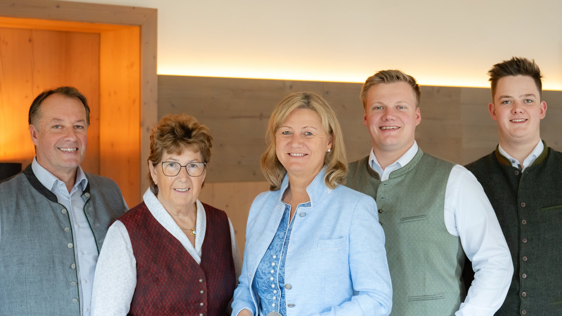 Five people wearing traditional Bavarian clothing in a modern room