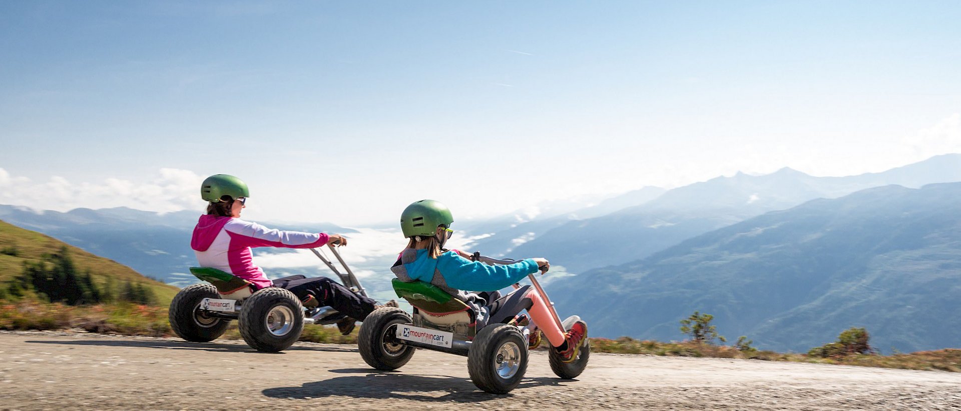 4 Sterne Hotel in Salzburgerland: Smaragdhotel Tauernblick Zwei Personen fahren Mountaincarts auf einem Bergweg mit Panoramablick