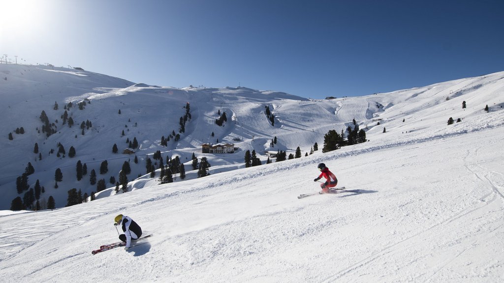 Skiing holidays in Salzburgerland: Smaragdhotel Tauernblick Two skiers skiing down a snowy mountain under clear blue sky