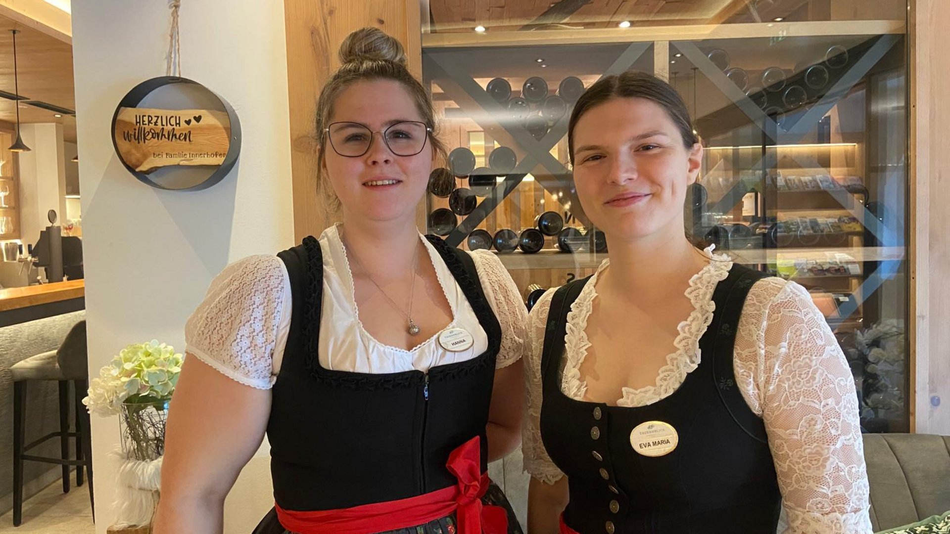 Wildkogel: Hotel mit Blick für das Besondere Zwei Frauen in traditionellen Trachten mit Namensschildern in einem Holzinnenraum