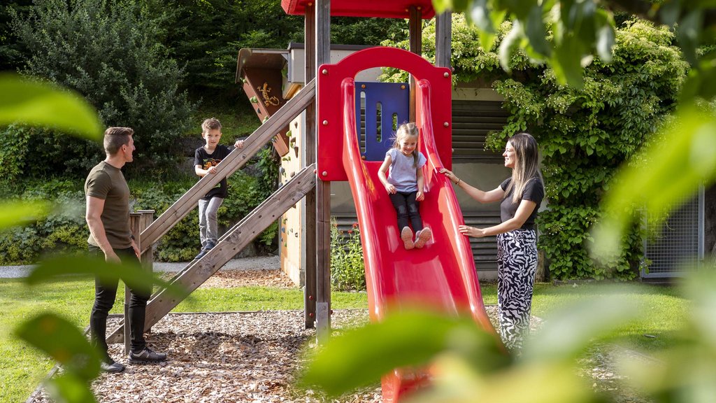 Familienhotel im Salzburger Land: Smaragdhotel Tauernblick Kinder spielen auf roter Rutsche im Garten mit zwei Erwachsenen