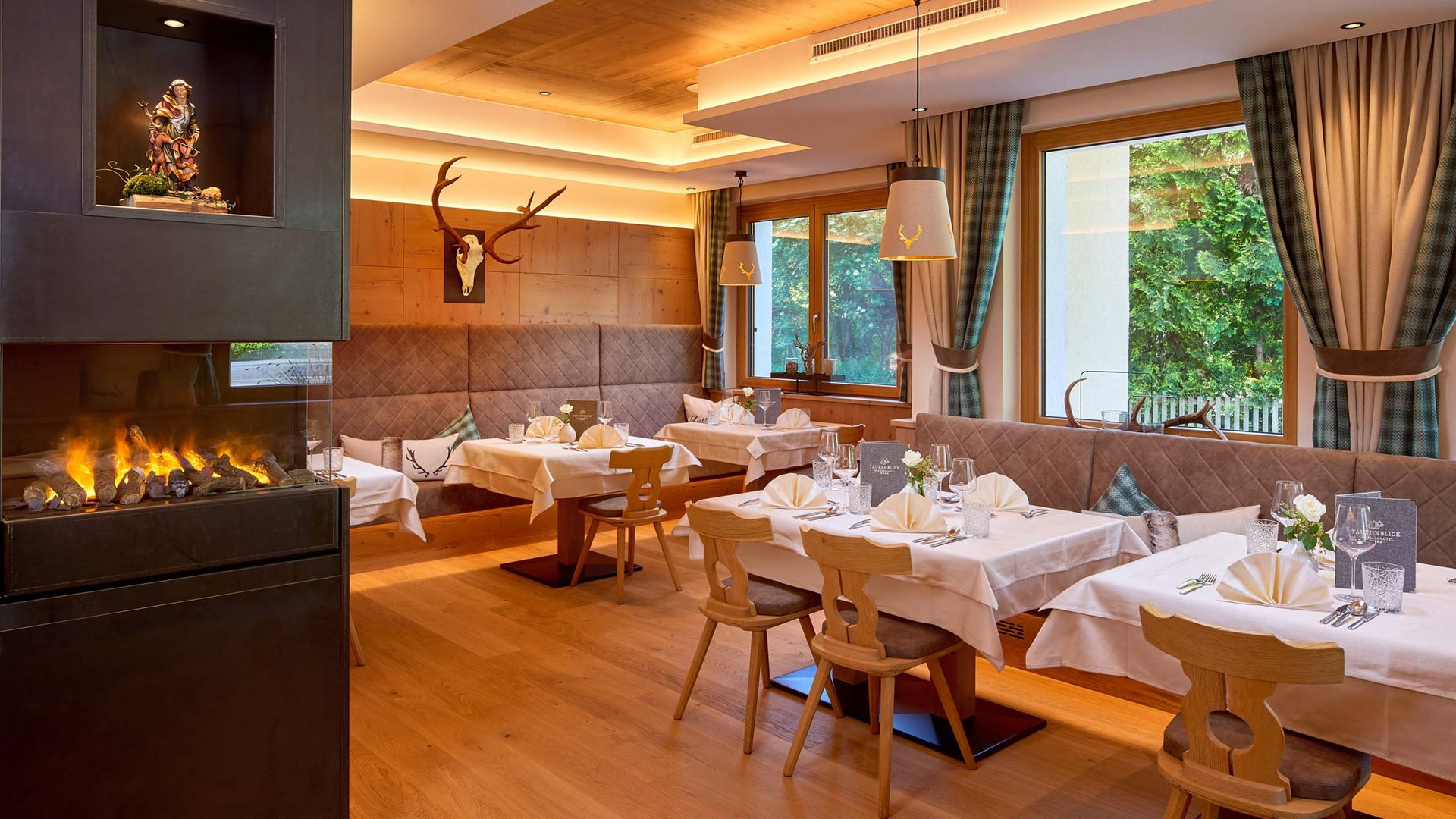 Salzburgerland: wellness hotel with 4 stars and cuisine Cozy restaurant area with wooden furniture, fireplace, and deer antlers on the wall