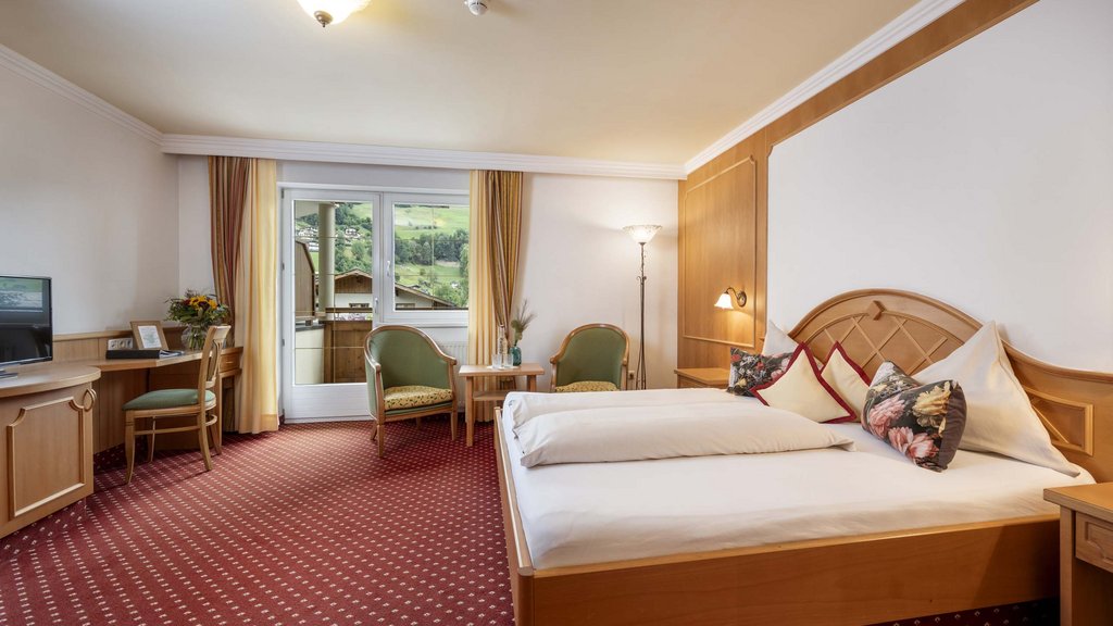 Bramberg am Wildkogel: accommodation Bright hotel room with double bed, seating area, and balcony overlooking mountains
