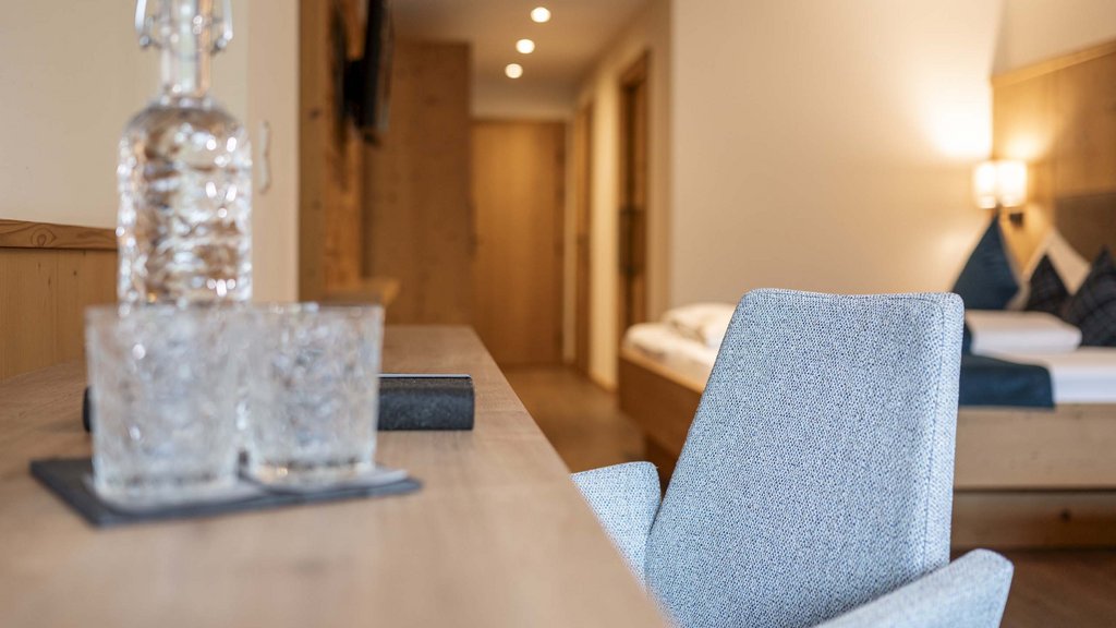 Bramberg am Wildkogel: accommodation Modern room with glass bottle, glasses, chair, and couch in the background