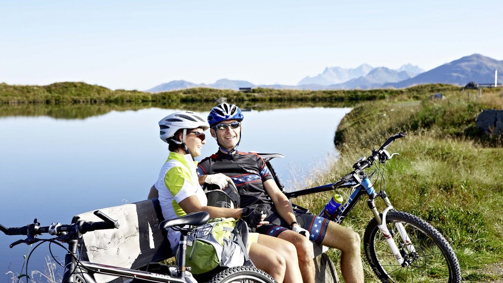Hohe Tauern National Park: holiday for bikers Two cyclists sitting on a bench by a lake with mountains in the background