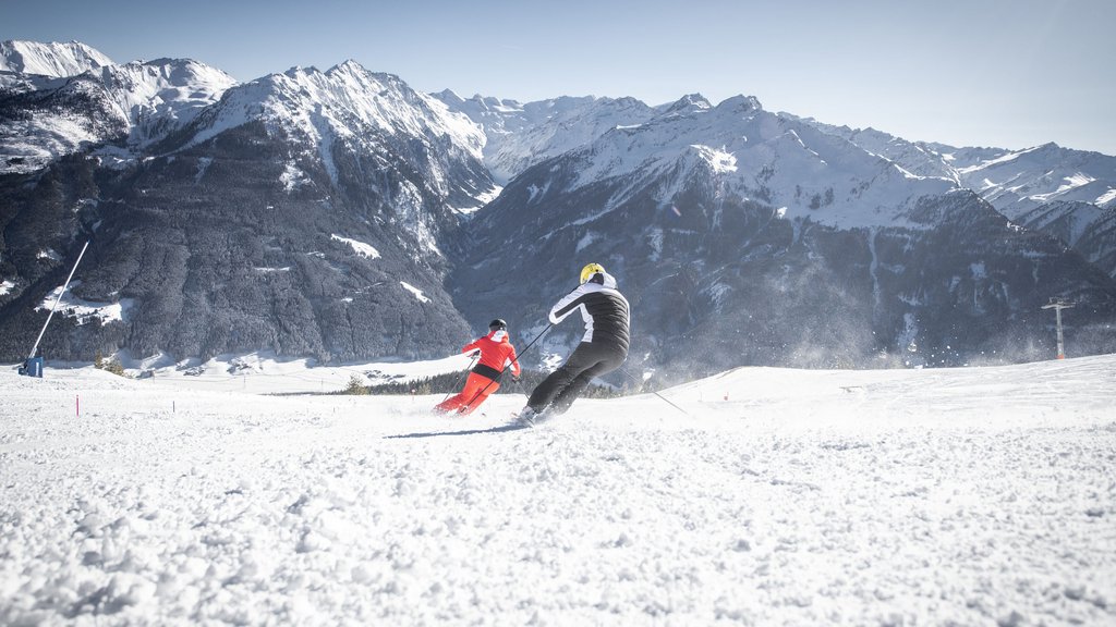 Skiing holidays in Salzburgerland: Smaragdhotel Tauernblick Two skiers skiing on snowy slope with sunny mountain backdrop
