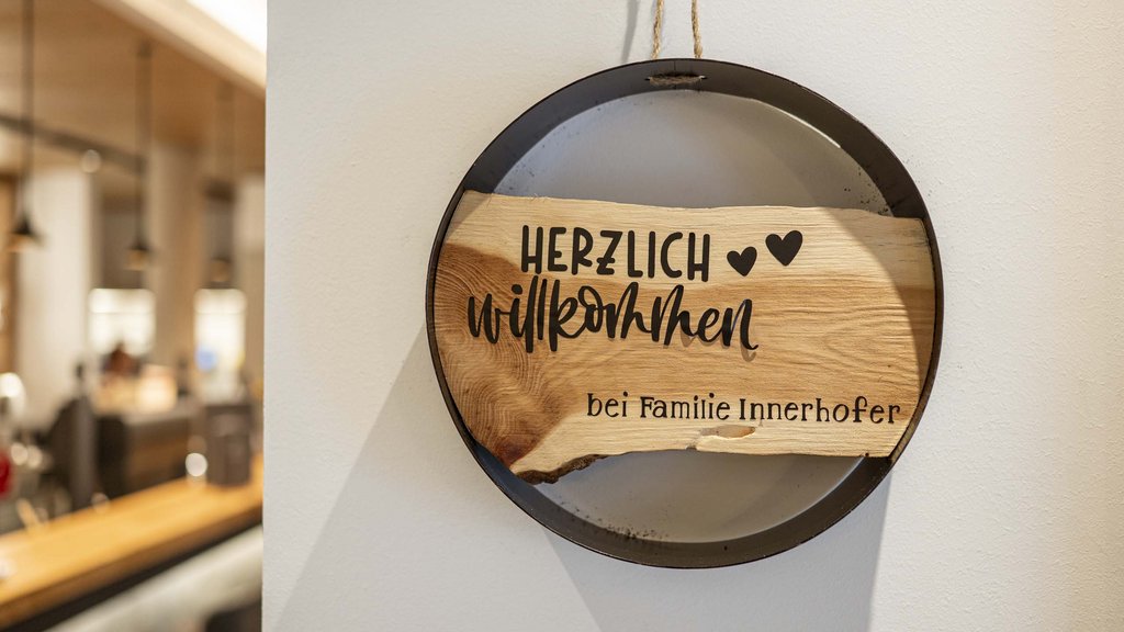 Smaragdhotel Tauernblick – Ihr 4-Sterne-Hotel am Wildkogel Holzschild mit Willkommenstext hängt an weißer Wand