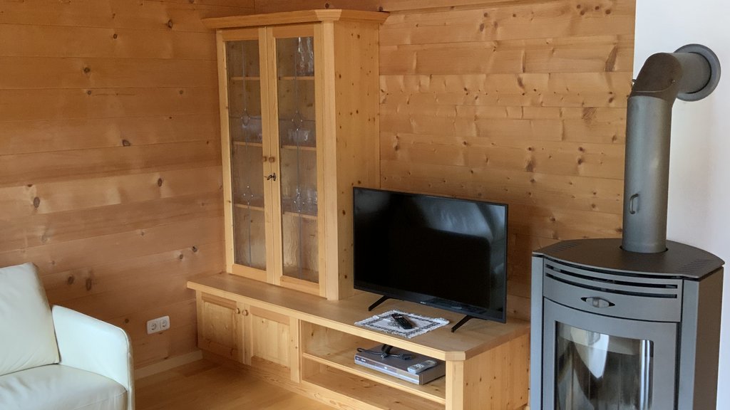 Das Ferienhaus Smaragd: ein wahres Juwel Wohnzimmer mit Holzofen, TV, Vitrine und einem Tisch mit zwei Gläsern