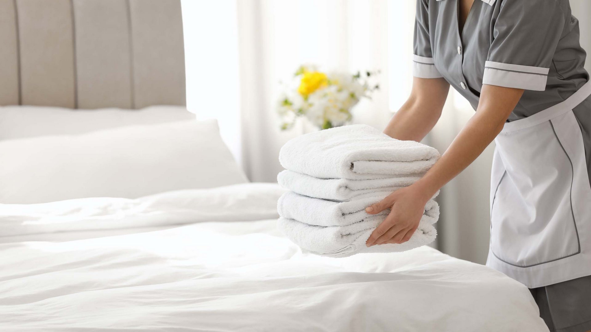 Salzburgerland: hotel jobs Housekeeper placing fresh white towels on a freshly made bed