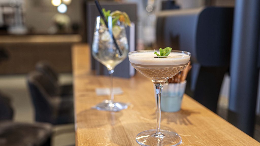 Wellnesshotel Salzburgerland: Smaragdhotel Tauernblick Cocktailglas mit Schaum und Minzblatt auf Holztheke im Restaurant