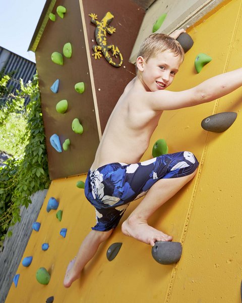 Family hotel in Bramberg: Smaragdhotel Tauernblick Boy climbing outdoor climbing wall on sunny day