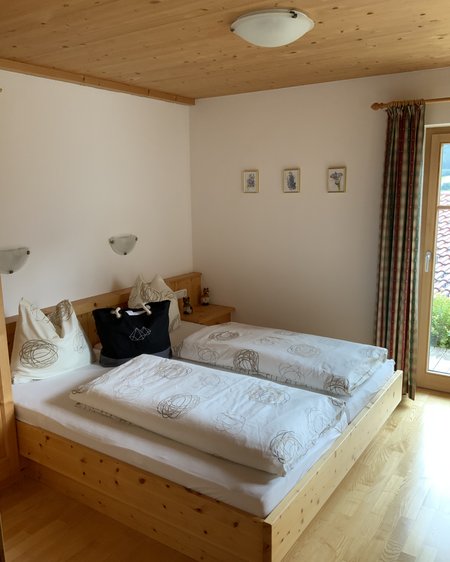 Das Ferienhaus Smaragd: ein wahres Juwel Schlafzimmer mit Holzbett, weißen Bettdecken und kleinem Fenster mit Blick nach draußen