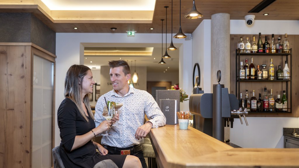 Ihr Pärchenurlaub in Österreich Paar sitzt an der Bar und genießt Drinks in gemütlicher Atmosphäre