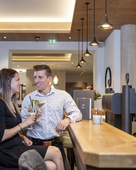 Ihr Pärchenurlaub in Österreich Paar sitzt an der Bar und genießt Drinks in gemütlicher Atmosphäre