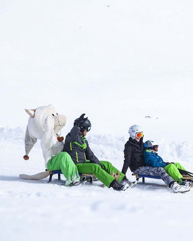 4 Sterne Hotel in Salzburgerland: Smaragdhotel Tauernblick Menschen und eine Person in Tierkostüm rodeln zusammen im Schnee