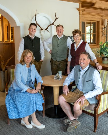 Wildkogel: Hotel mit Blick für das Besondere Fünf Personen in traditioneller bayerischer Tracht sitzen um einen Tisch in gemütlichem Raum