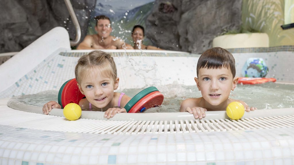 Wasserspaß im Hotel in Österreich mit Pool Kinder im Schwimmbecken mit Erwachsenen im Hintergrund