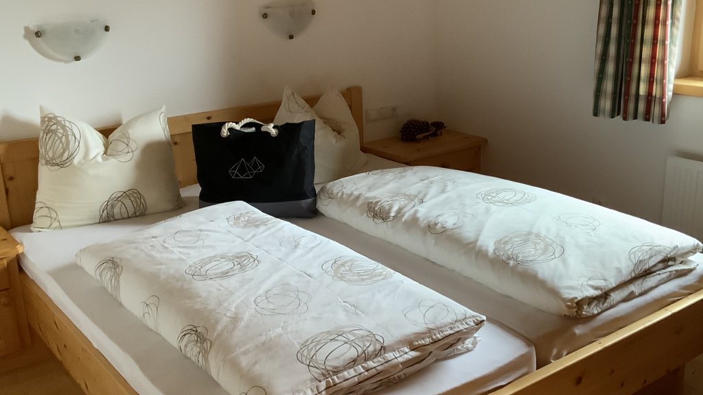 Das Ferienhaus Smaragd: ein wahres Juwel Holzbett mit zwei weißen Bettdecken und Kissen in einem schlichten Schlafzimmer