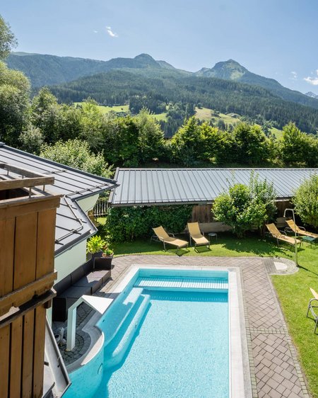 Your couples’ holiday in Austria Outdoor pool with lounge chairs and mountain view on a sunny day