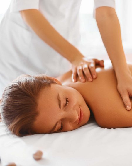 Langlaufurlaub Österreich: Smaragdhotel Tauernblick Frau liegt entspannt bei Rückenmassage auf Massagetisch