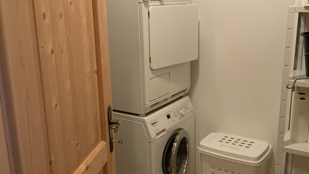 Das Ferienhaus Smaragd: ein wahres Juwel Waschraum mit gestapelter Waschmaschine und Trockner, Wäschekörben und Holztür