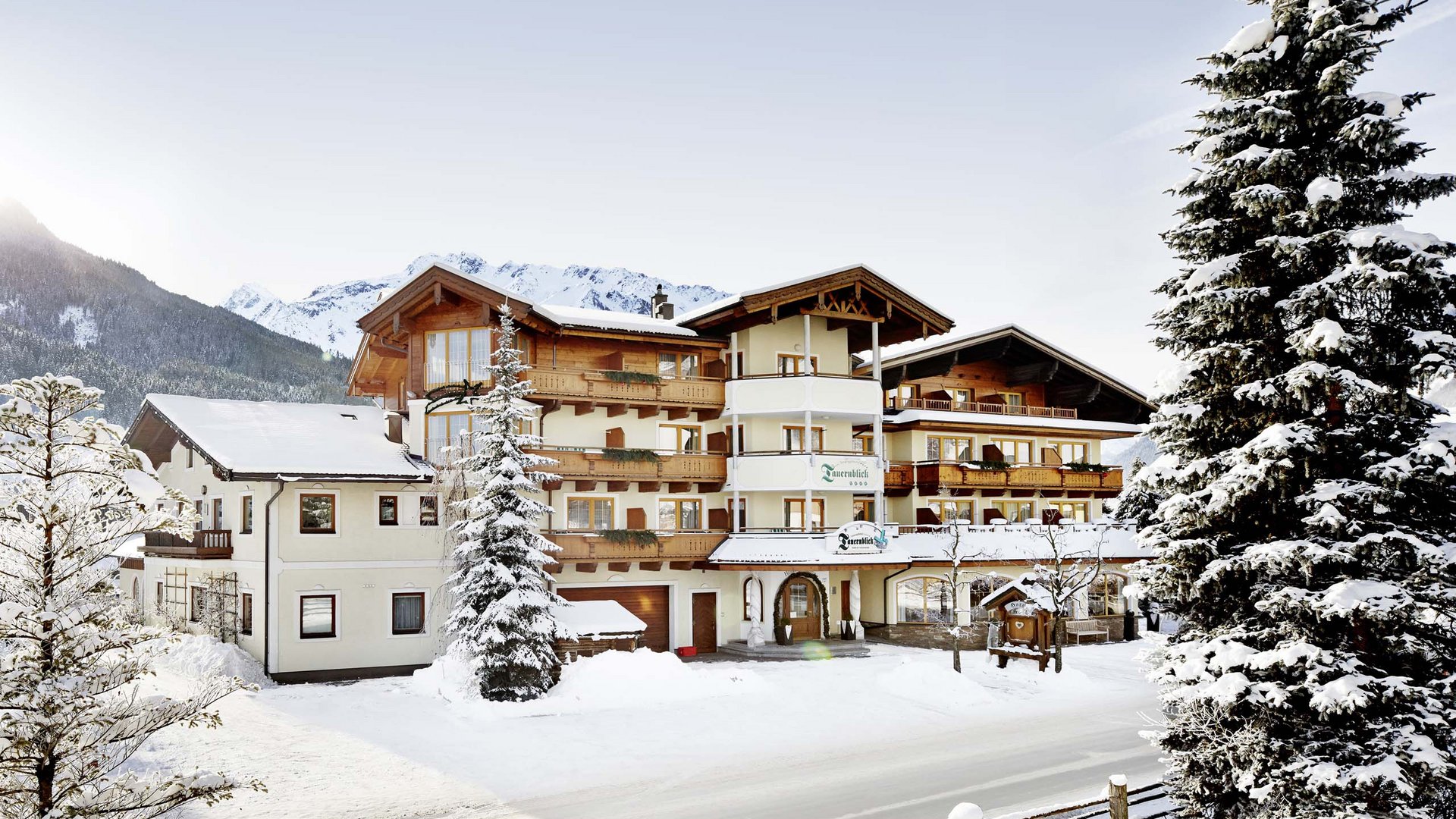 Unterkunft Wildkogel: Smaragdhotel Tauernblick Hotel in verschneiter Berglandschaft mit Tannenbäumen und klarem Himmel