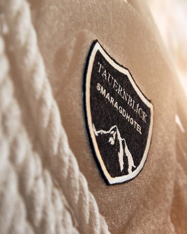 Wildkogel: Hotel mit Blick für das Besondere Close-up auf das Taufersblick Smaragdhotel Logo auf Stoff