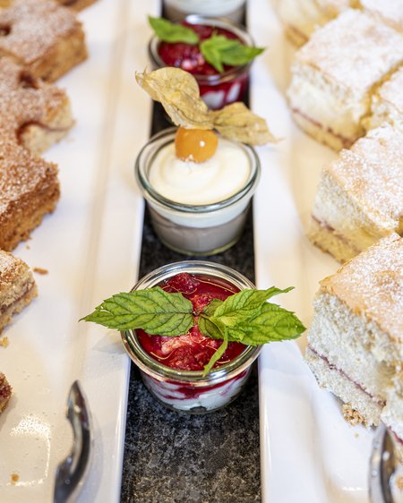 Salzburgerland: Wellnesshotel mit 4 Sternen und Kulinarium Verschiedene Kuchenstücke und Becher mit Creme und Beeren auf weißen Tellern