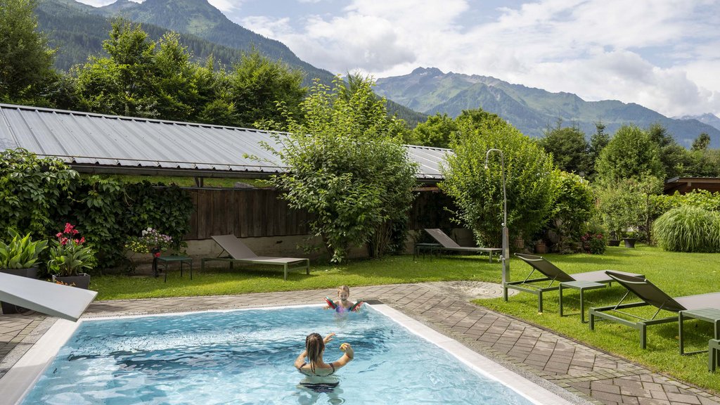 Wellnesshotel Salzburgerland: Smaragdhotel Tauernblick Kinder spielen in einem Pool mit Bergpanorama und Liegestühlen im Garten