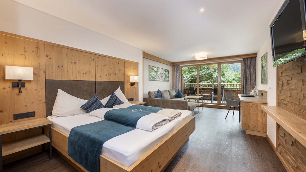 Smaragdhotel Tauernblick – Ihr 4-Sterne-Hotel am Wildkogel Modernes Hotelzimmer mit Doppelbett, Sofa, großem Fernseher und Balkon