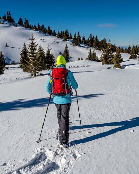 Smaragdhotel Tauernblick – Ihr 4-Sterne-Hotel am Wildkogel Person beim Schneeschuhwandern auf verschneitem Berg mit blauem Himmel